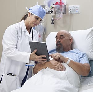 Provider talks to man in pre-op hospital room.