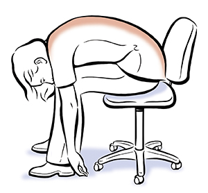 Mujer sentada en una silla inclinada hacia adelante con el pecho sobre las piernas y los brazos colgando hacia abajo.